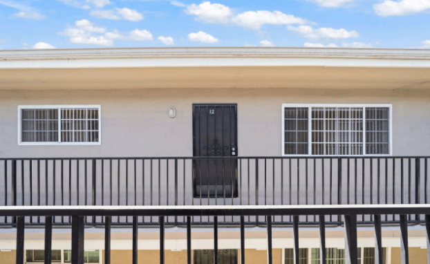 A building with a black door and windows with white bars.